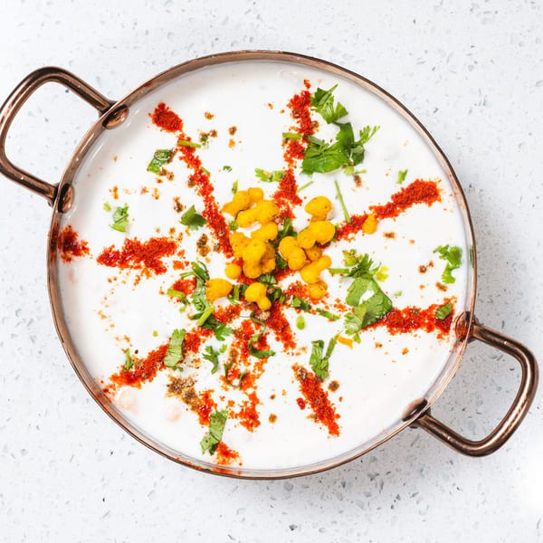 Gulab Indian Bistro's Indian raita, a yogurt dish, garnished with red spices, cilantro, and yellow boondi.
