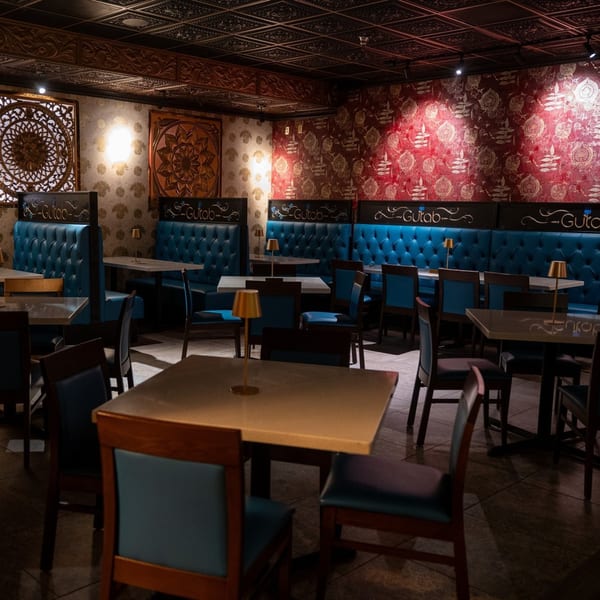Gulab Indian Bistro's dining room with blue booths, tables, chairs, and ornate wall decor.